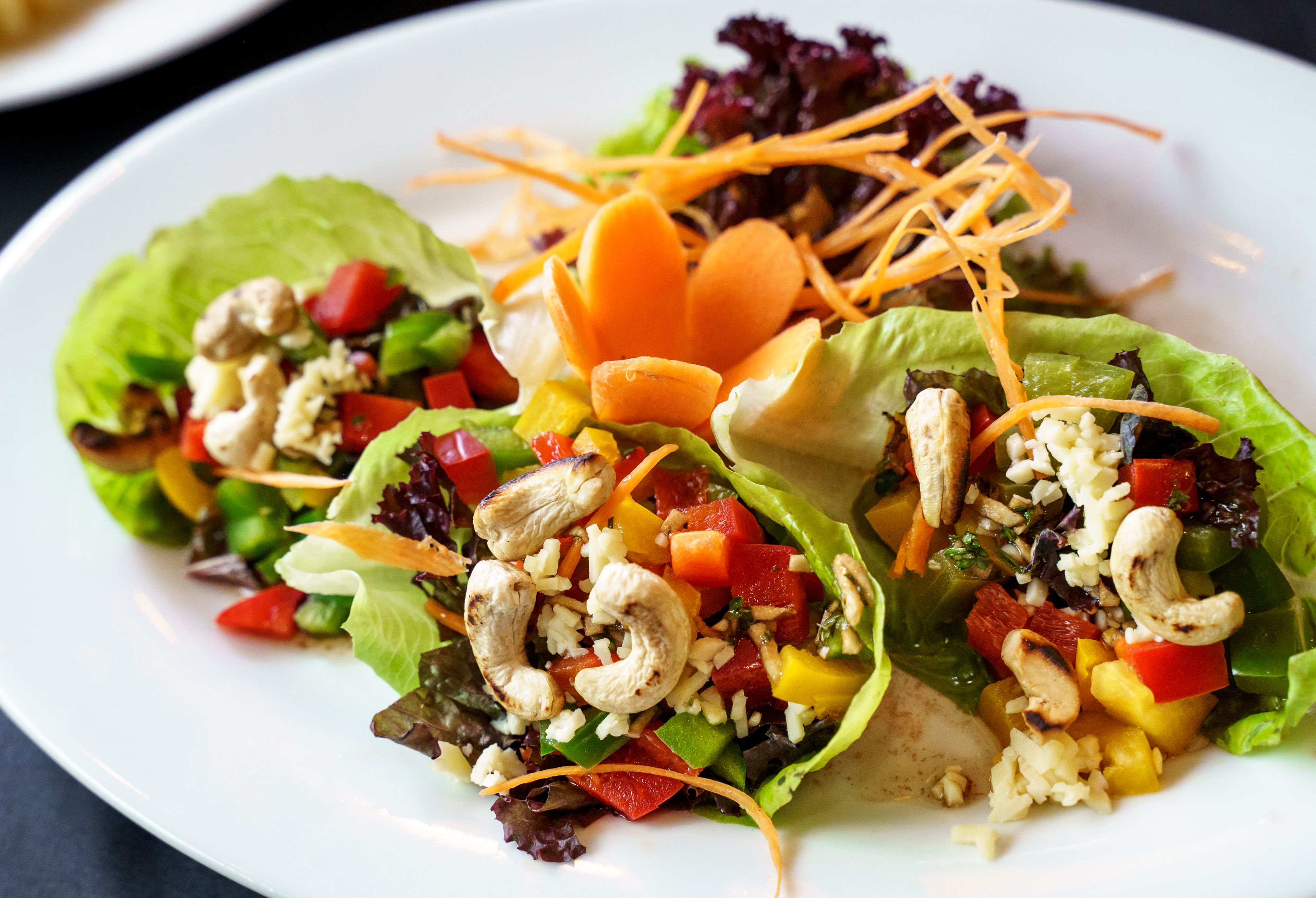 Un plato de ensalada colorida con diversas verduras y nueces de anacardo.