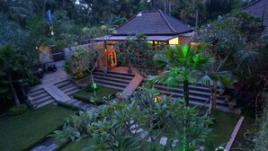 A house with a tiled roof, surrounded by lush greenery and a well-maintained garden. - Ubud Raya Boutique Hotel (Ubud)