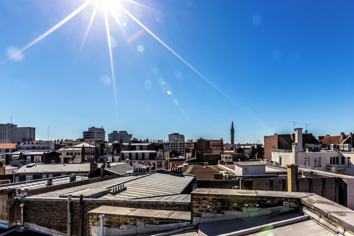A cityscape with multiple rooftops and buildings under a clear sky.