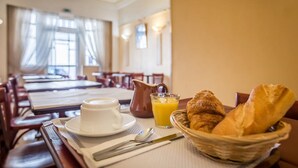 A breakfast setting with a cup, jug, and basket of croissants on a table. - Hotel Saint Maurice (Lille)