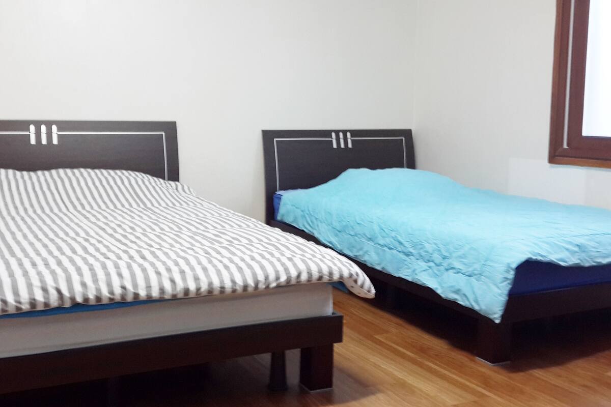 Two single beds with wooden frames and headboards, a striped pillow, and a blue blanket.