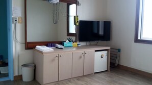 Une chambre avec un meuble en bois, un petit réfrigérateur, une télévision et une fenêtre donnant sur un beau paysage.