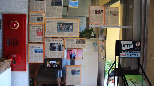 Un mur orné de plusieurs affiches d’information et d’une boîte rouge contenant un déclencheur d’alarme incendie.