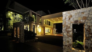 A modern hotel with a stone facade, large windows, and a well-lit entrance. - Espira Kinrara (Puchong)