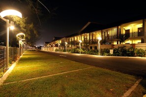 A well-lit hotel corridor with multiple balconies and a grassy area. - Espira Kinrara (Puchong)