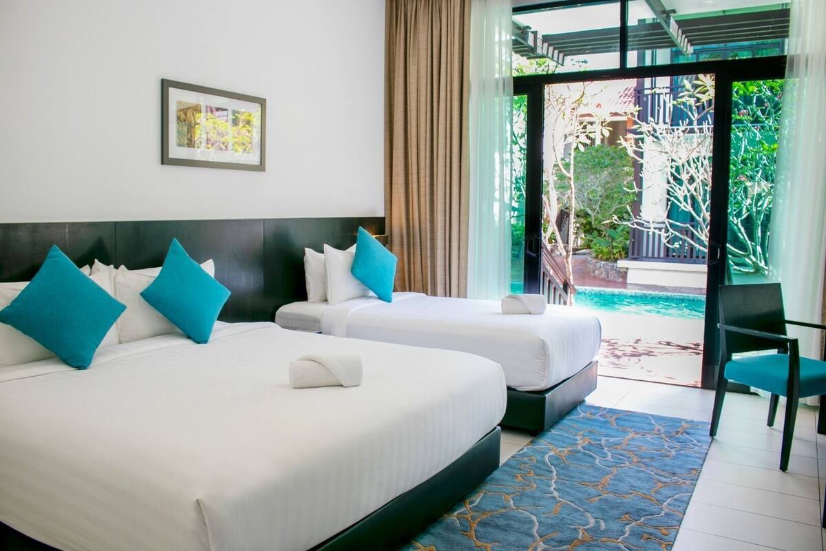 A hotel room with two beds, a large window, and a view of a swimming pool.