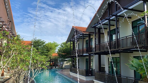 A swimming pool with water features, surrounded by buildings with balconies and railings. - Espira Kinrara (Puchong)