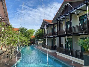 A swimming pool with water features, surrounded by buildings with balconies and railings. - Espira Kinrara (Puchong)