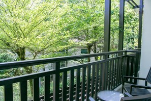 A balcony with a view of trees and a building in the background. - Espira Kinrara (Puchong)
