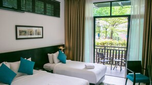 A hotel room with two beds, a balcony with chairs, and a view of greenery. - Espira Kinrara (Puchong)