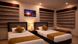 A hotel room with two beds, a nightstand with a lamp, and a painting on the wall. - Panorama Amman Hotel (Amman)