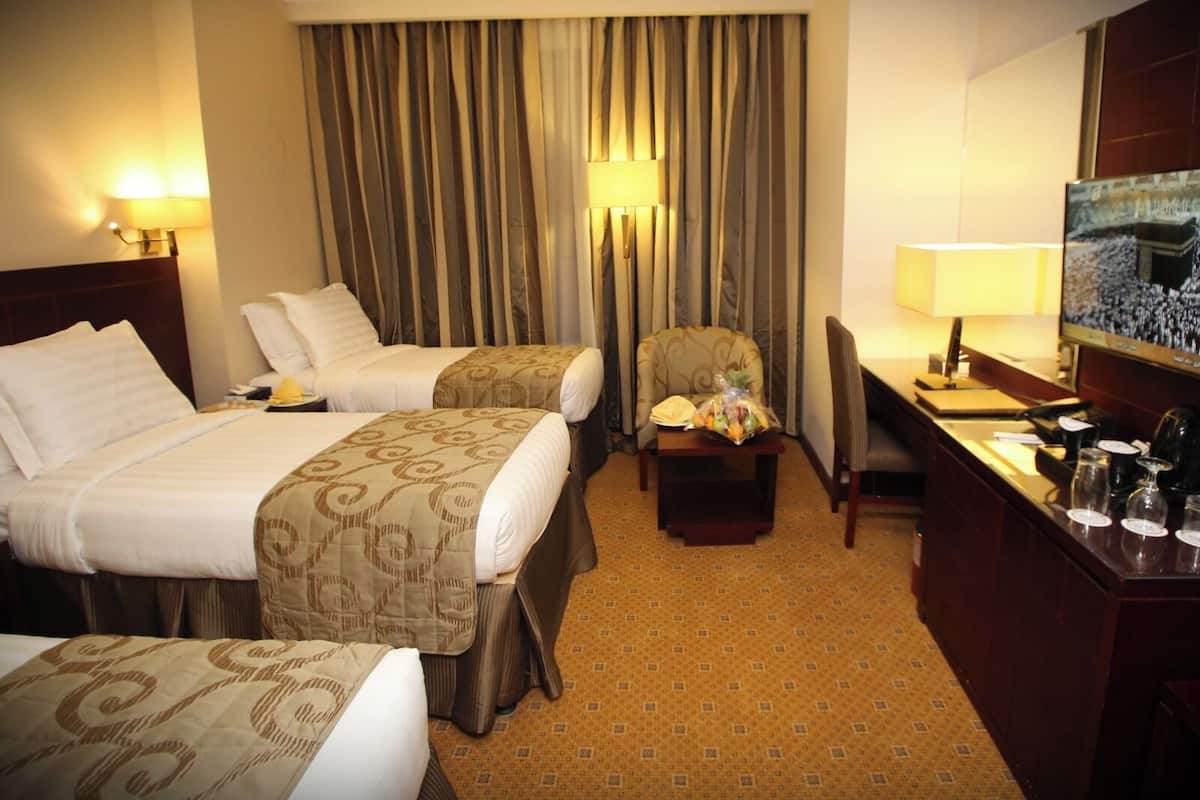 Een hotelkamer met twee bedden, een bureau met stoel, een televisie en een minibar.