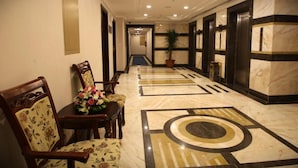 Un vestíbulo de hotel con suelo de mármol, una recepción y una zona de estar con arreglos florales.