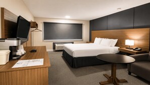 A hotel room with a bed, desk, chair, TV, and a window. - SureStay by Best Western Smithers (Smithers)