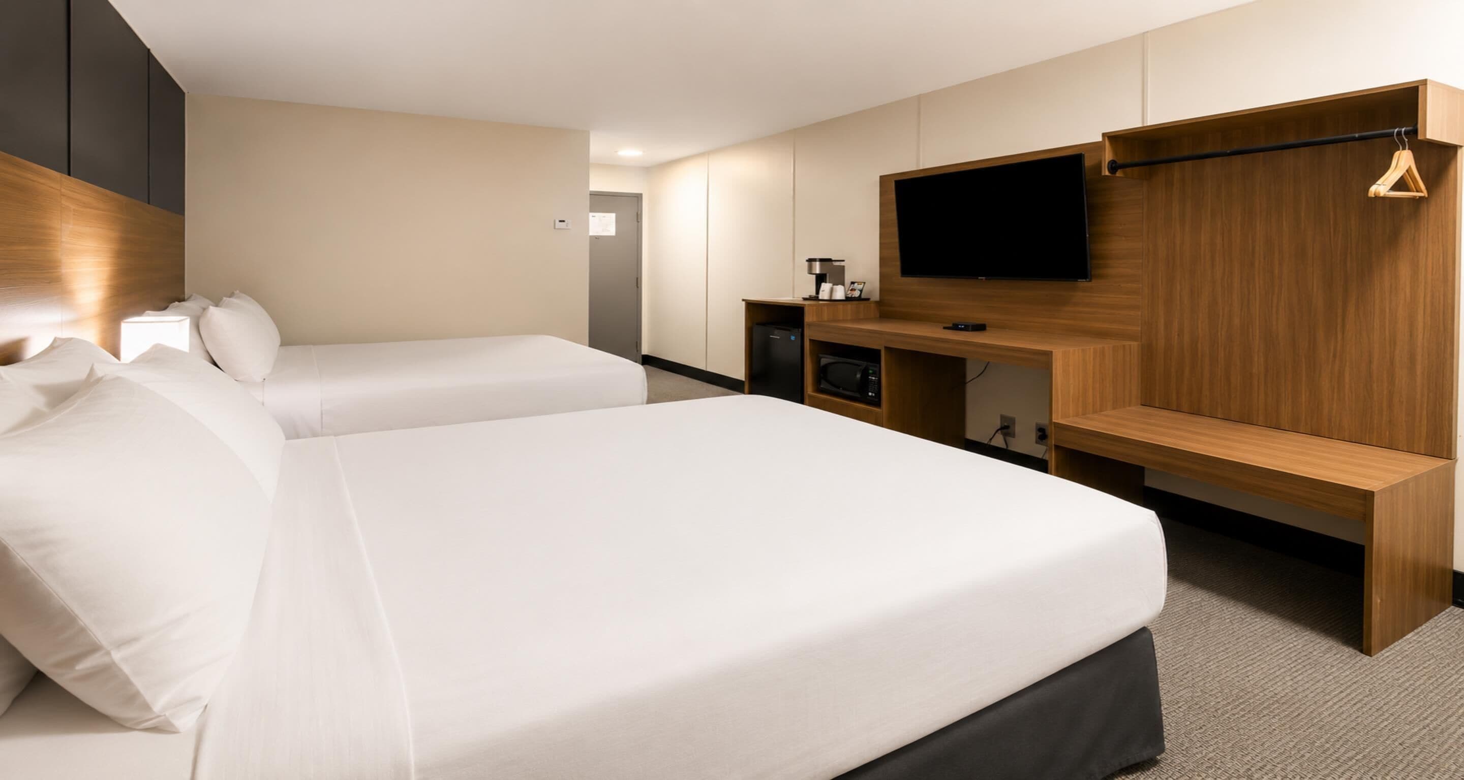 Une chambre d’hôtel avec deux lits, une télévision, un bureau et une armoire.