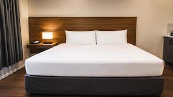 Una habitación de hotel con una cama grande, una mesita de noche con una lámpara y un teléfono.