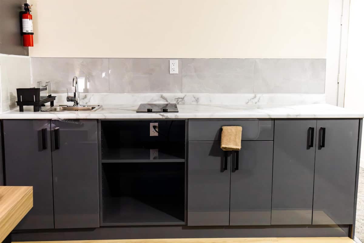 A modern kitchen with a marble countertop, black cabinets, and a black island.