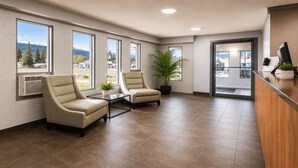 A reception area with two armchairs, a potted plant, and a reception desk. - SureStay by Best Western Smithers (Smithers)