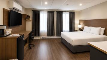 Een hotelkamer met een bed, bureau, televisie en een koffiezetapparaat.