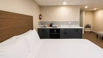 Une chambre d’hôtel avec un lit, une kitchenette et une chaise.