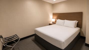 A hotel room with a large bed, a nightstand with a lamp, and a chair.