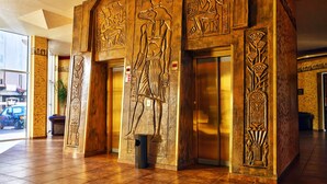 A lobby with Egyptian-themed wall carvings and a trash bin. - Amfora Hotel (SUNNY BEACH)