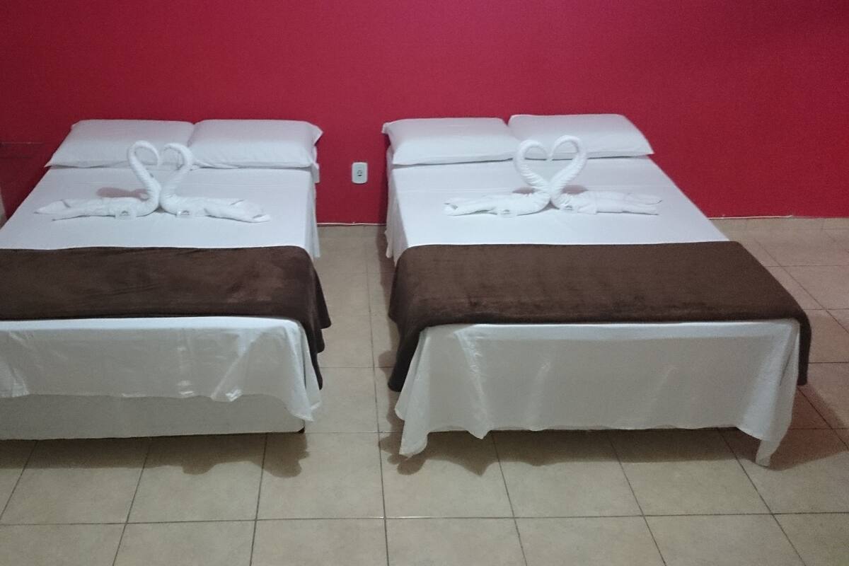 Two single beds with white linens and brown throw blankets, a red wall, and a tiled floor.
