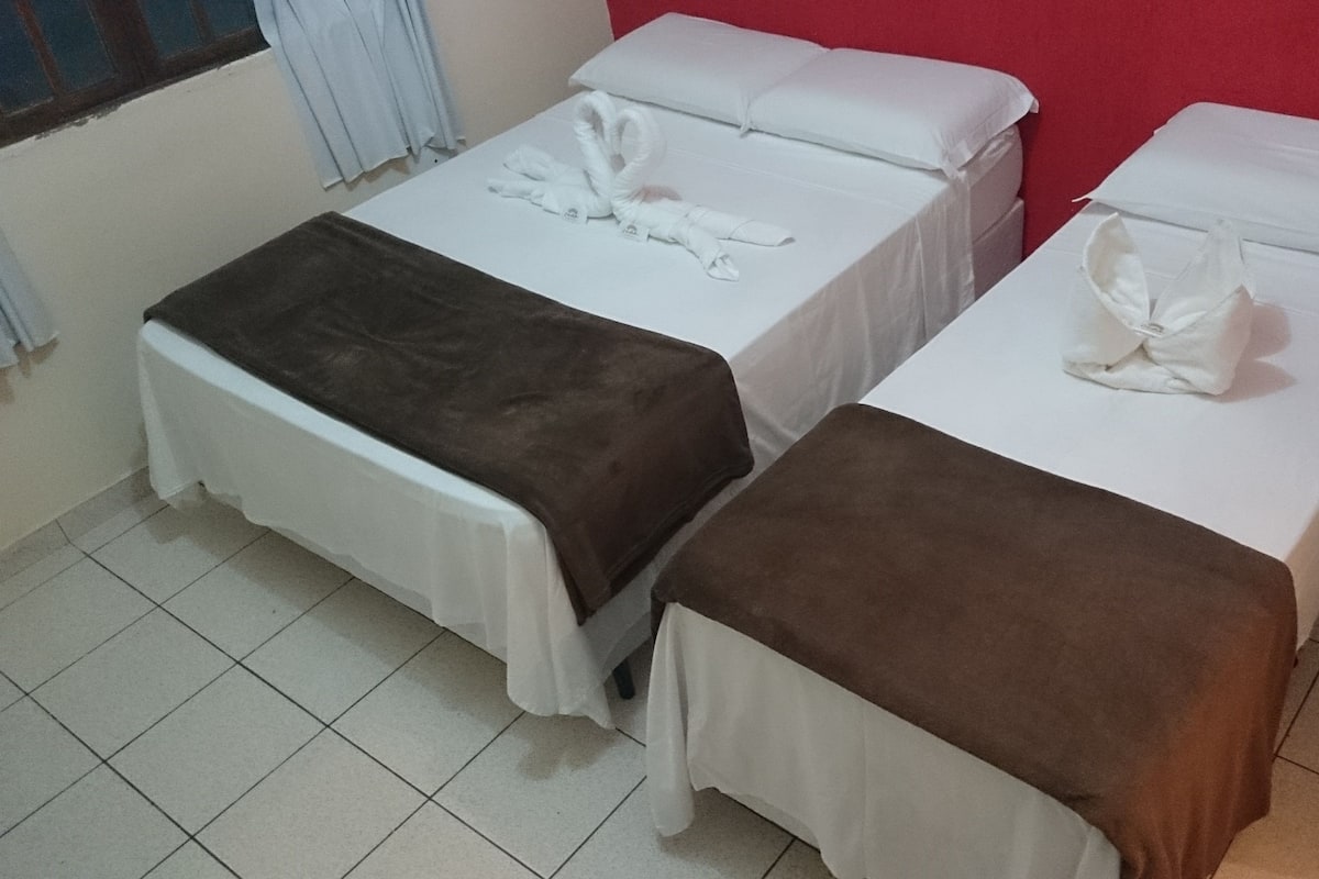A hotel room with two beds, each with a white mattress and brown blanket.