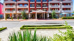 Un hotel de varios pisos con fachada roja y blanca, balcones y una entrada central con un letrero.