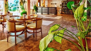Un vestíbulo de hotel con mostrador de recepción, zona de estar y plantas en macetas.