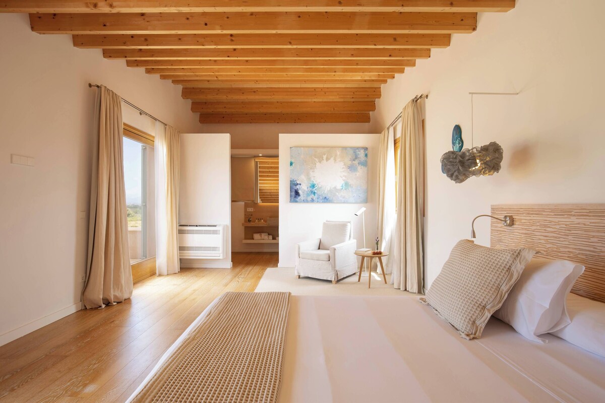 Une chambre avec un plafond en bois, un lit, une chaise, un tableau et une vue sur une salle de bain.