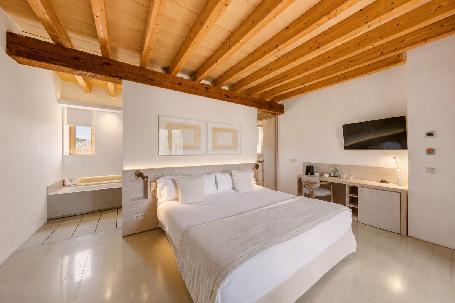 Un dormitorio con una cama grande, un escritorio, un televisor y una ventana.