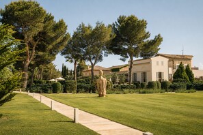 Un jardin bien entretenu, agrémenté d’une statue, d’un sentier et d’un bâtiment dont le toit est recouvert de tuiles.