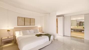 A modern bedroom with a large bed, bedside tables, a nightstand, a mirror, and a bathroom with a vanity and sink.