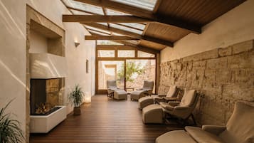 A spacious indoor area with a fireplace, multiple seating options, and a view of the outdoors.