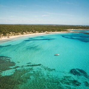 A coastal landscape with clear turquoise waters, a boat, and a beach area. - Hotel Fontsanta Thermal Spa & Wellness, adults only – Preferred Hotels & Resorts (Campos)