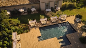 Vista aérea de un resort con piscina, mobiliario exterior y exuberante vegetación.