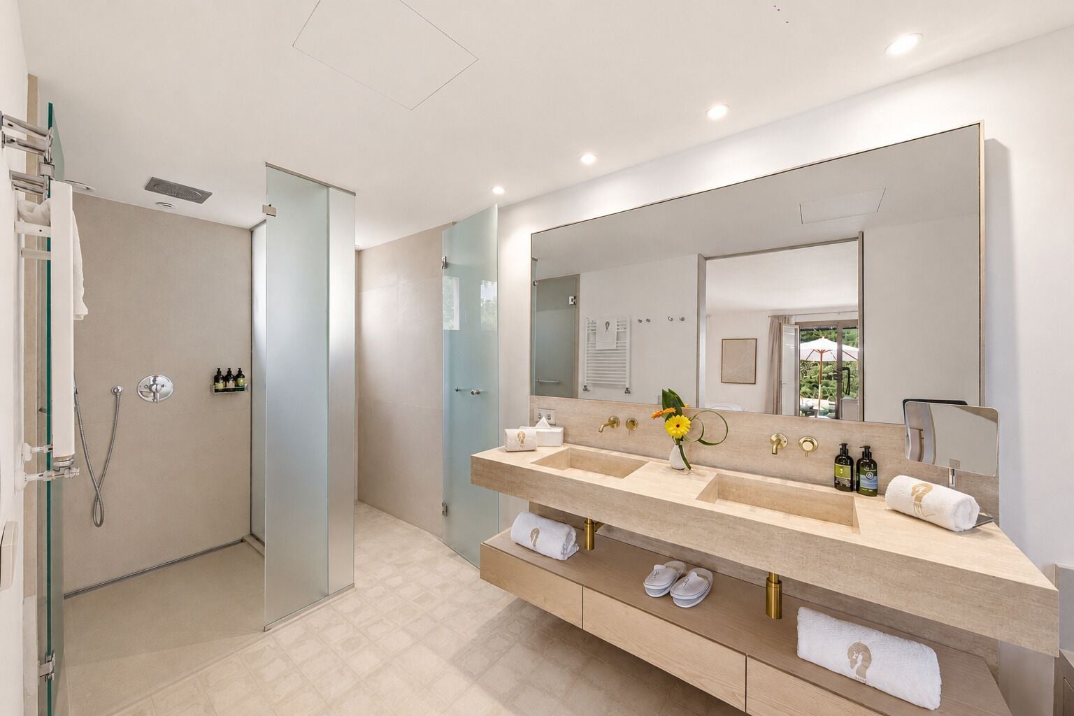 Un baño moderno con cabina de ducha, un espejo grande y un mueble de tocador con doble lavabo.