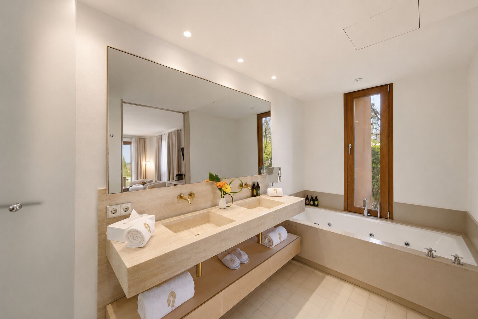 A modern bathroom with a double sink vanity, a large mirror, and a bathtub.