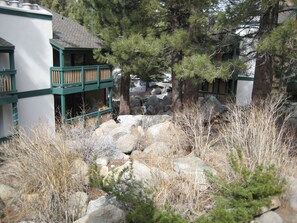 A building with a green balcony, surrounded by trees and rocks. - Sherwin Villas by Mammoth Res Bureau (Mammoth Lakes)