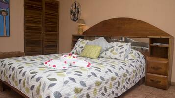 Un dormitorio con cama, cabecera de madera, mesitas de noche y un armario.