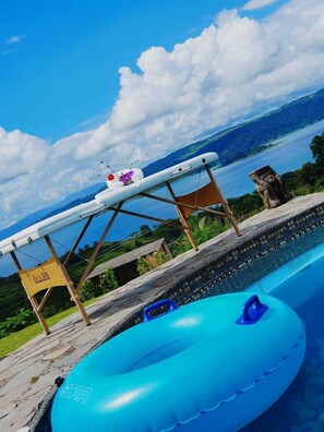 A pool area with a floating lounge chair, a floating ring, and a stone sculpture.