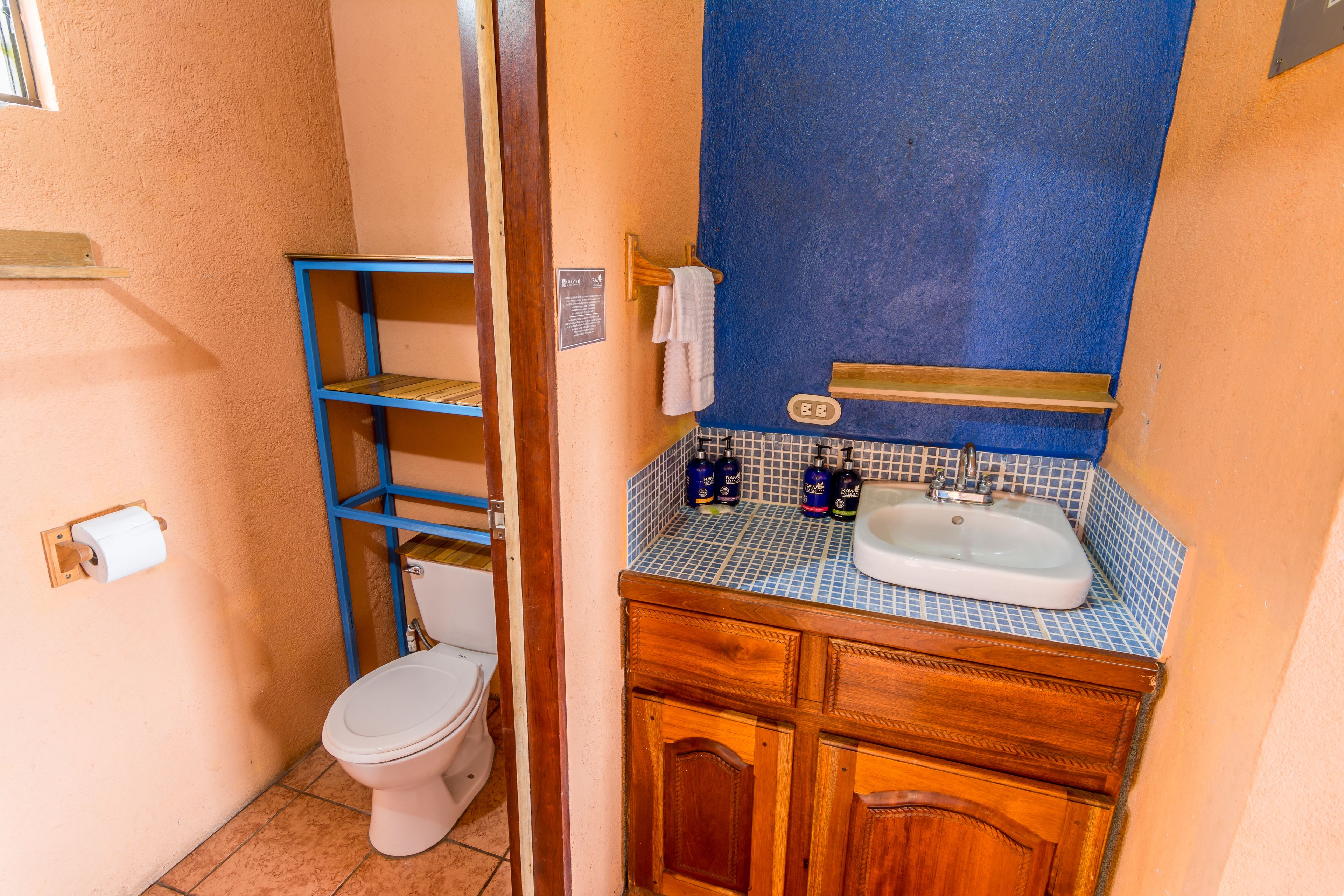 Un baño con inodoro, lavabo y encimera con azulejos azules.
