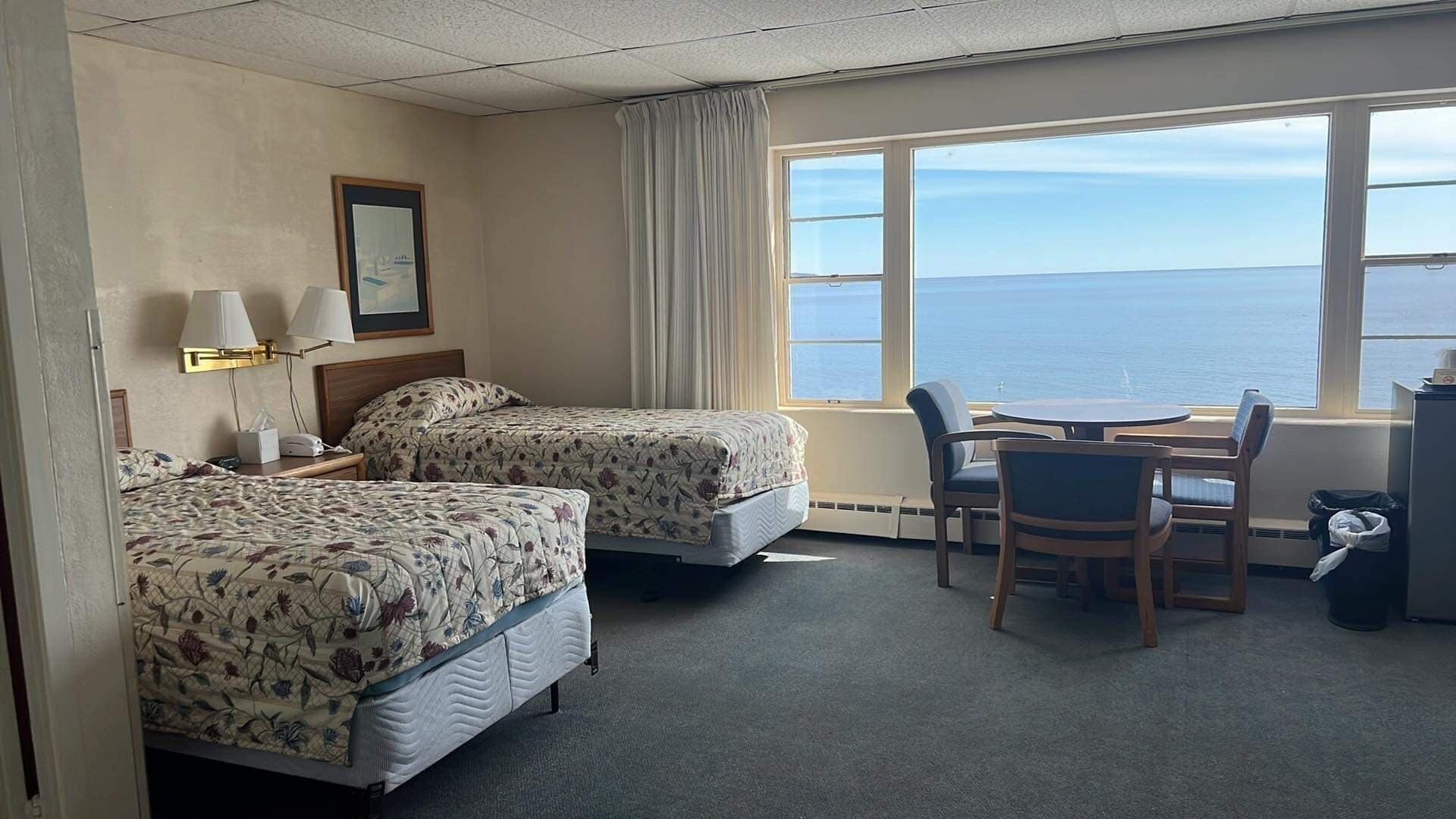 A hotel room with two beds, a desk, and a chair.