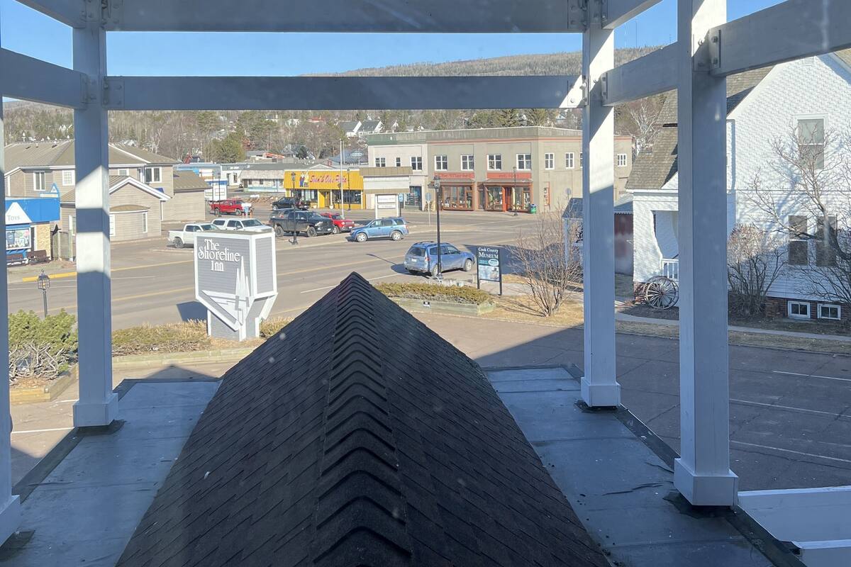 A covered outdoor area with a view of a town, including a gas station and a building with a sign that reads "The Shoreline Inn."