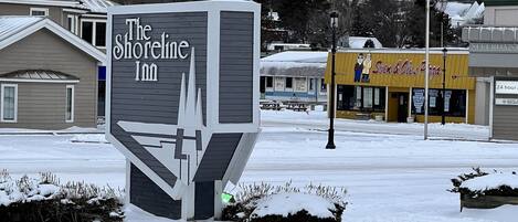 The Shoreline Inn sign with a modern design, surrounded by snow-covered ground and buildings in the background.
