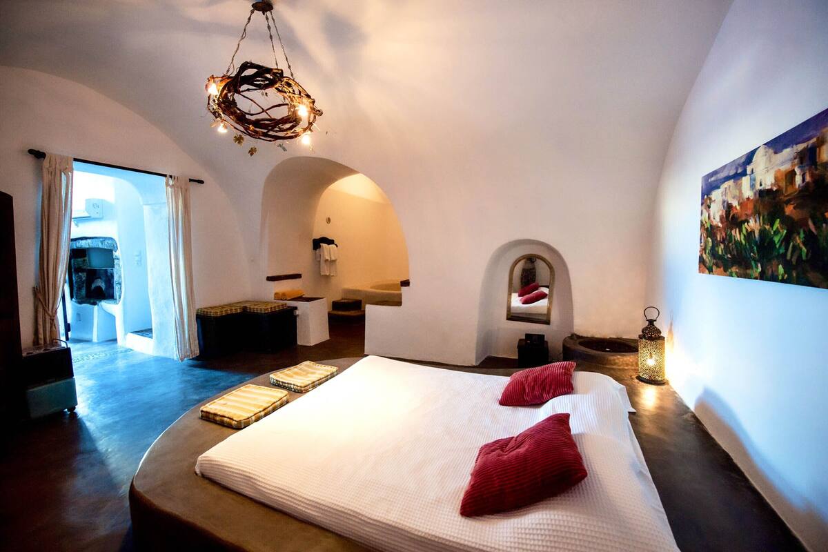 Une chambre spacieuse avec un grand lit, un luminaire suspendu et une vue sur l’extérieur.