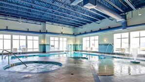 An indoor swimming pool with multiple lanes, a hot tub, and a water fountain.
