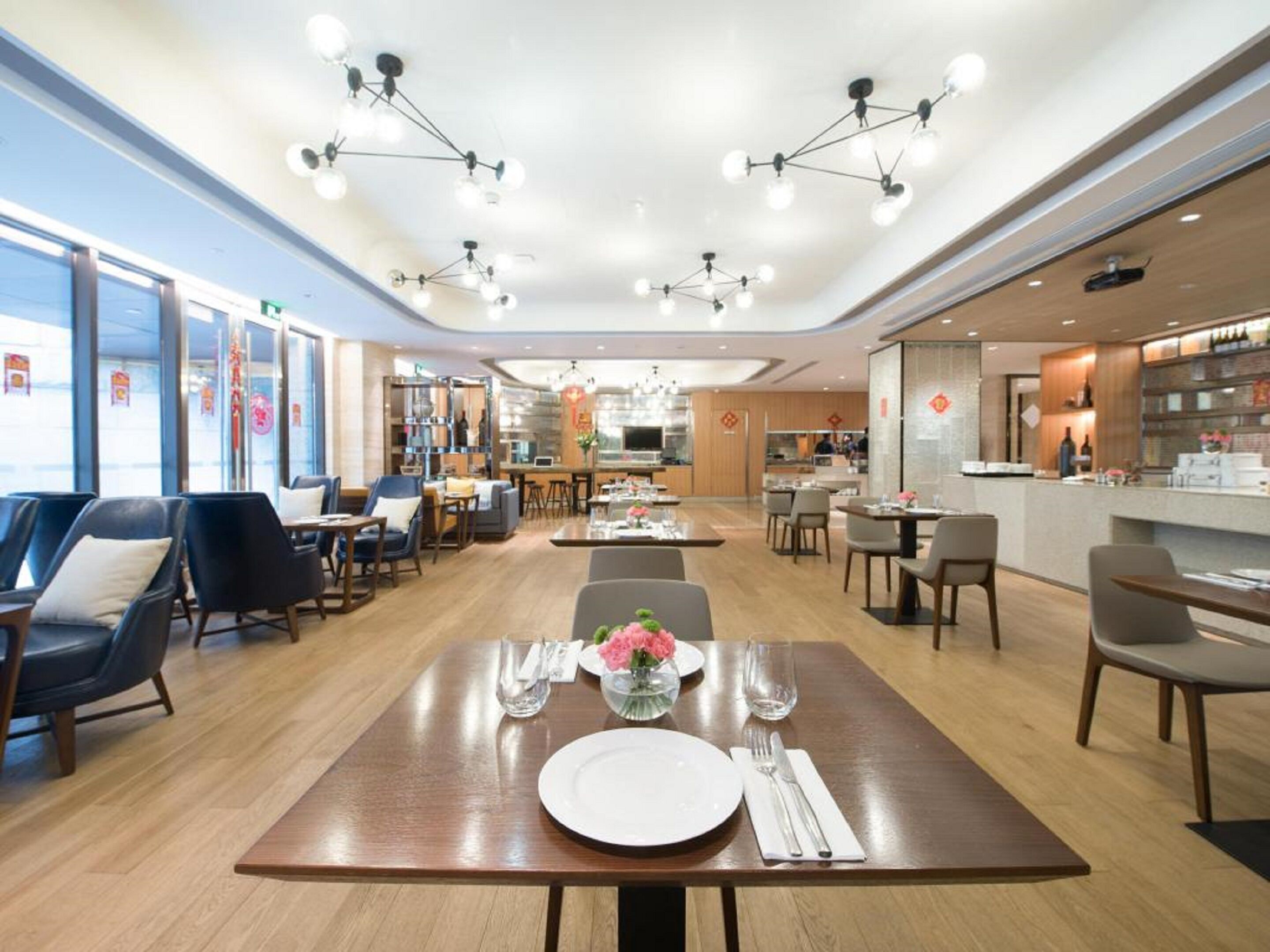 A spacious hotel dining area with multiple tables, chairs, and a bar area.