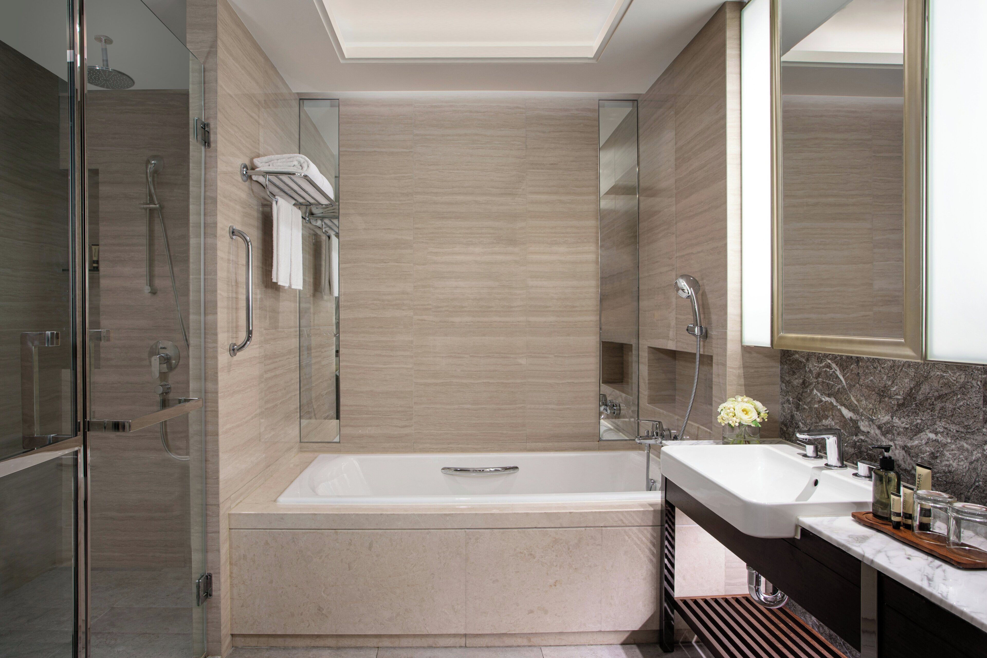 A modern bathroom with a freestanding bathtub, a glass shower enclosure, and a vanity with a marble countertop.